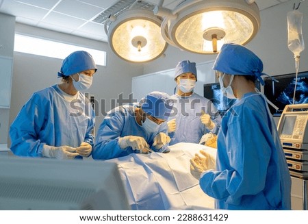Operation team with blue clothes compose of nurse and doctor help to treatment patient in operation room with serveral tools and instruments of life support in hospital. Royalty-Free Stock Photo #2288631429