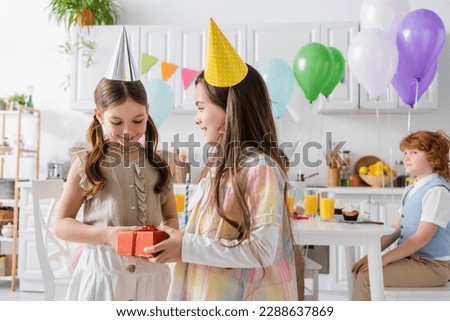 preteen girl congratulating pleased friend with happy birthday while holding gift box Royalty-Free Stock Photo #2288637869