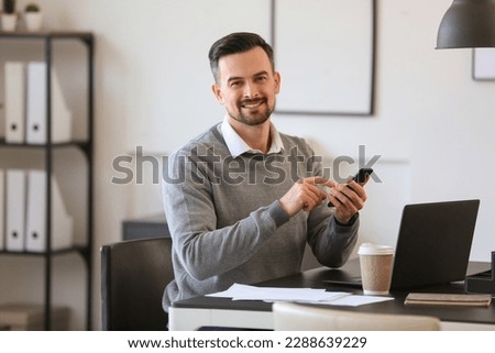 Handsome businessman working with mobile phone at table in office