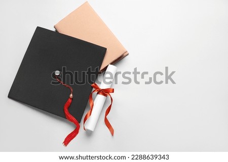 Diploma with red ribbon, graduation hat and book on white background