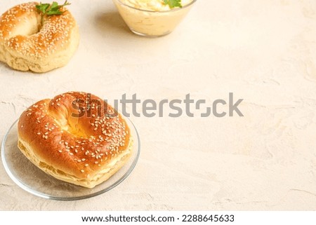 Plate with tasty bagels on light background