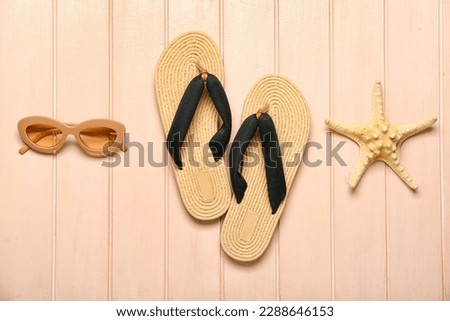 Flip-flops with sunglasses and starfish on beige wooden background Royalty-Free Stock Photo #2288646153
