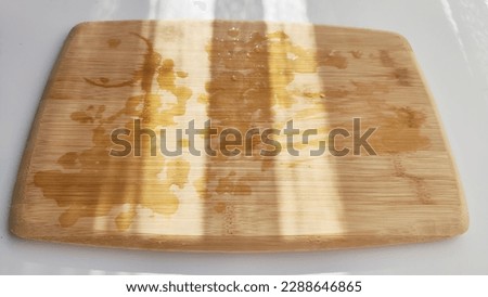 Cutting board made of natural bamboo on a white surface and with shade and light from sun. Abstract natural background, texture, frame and copy space. The concept of cooking with beautiful things
