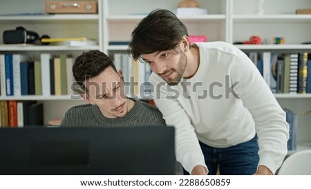 Two men students using computer studying at library university