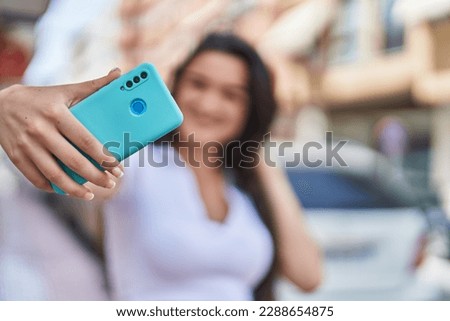 Young hispanic woman smiling confident making selfie by the smartphone at street