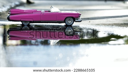 Side view pink diecast car, with reflection on water, bokeh foreground, isolated picture 