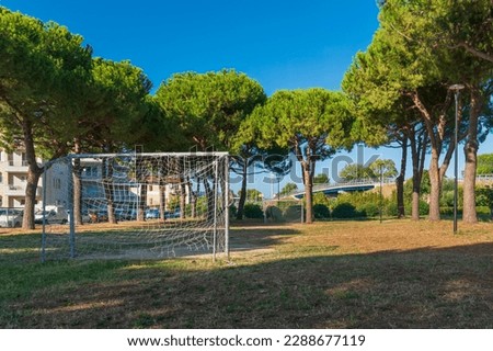 Football field in the open air against the background of houses in the city, clear sunny day, beautiful green crowns of trees against the blue sky, street football in Italy, healthy lifestyle