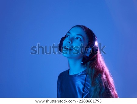 beautiful happy woman listening to music with headphones in neon light