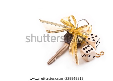 Car keys with gold bow and dice on a white background