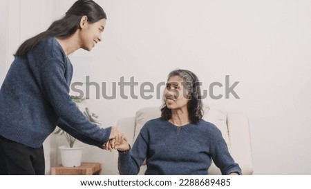 encouragement, helping hand, holding hands, Mother's day concept, young adult female daughter congratulate excited asian elderly mother at sofa with birthday anniversary, two generations family photo