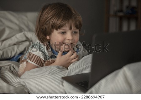 The child watches cartoons on the laptop before a sleep.Baby have a call and talking before a sleep on the the laptop. Toddler watch a movie before a sleep.