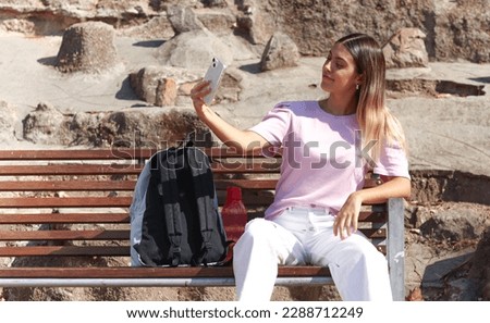 American plane. Teenage girl taking a selfie on a park bench.