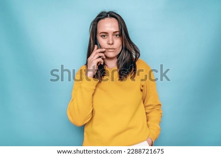 Black haired woman in yellow clothes calls on mobile phone