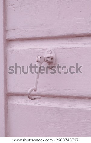 Vertical image of soft pink painted panelled wood and retaining hook