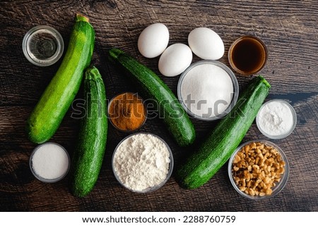 Zucchini Bread Ingredients on a Wood Table Background: Fresh zucchini, flour, walnuts, and other dessert bread ingredients