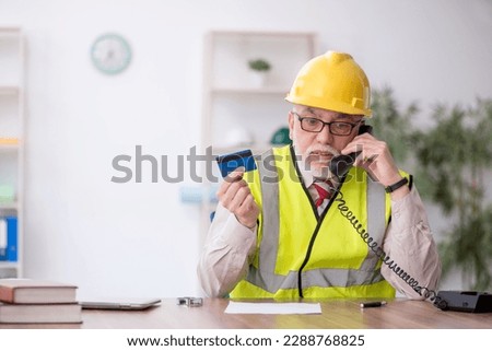 Old male architect holding credit card