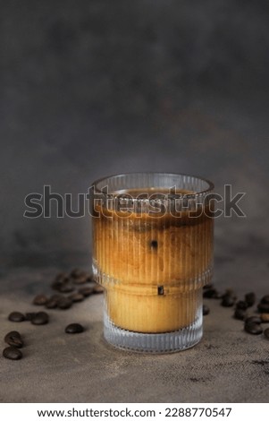 Tasty ice coffe with milk, cold drink in glass in dark background.