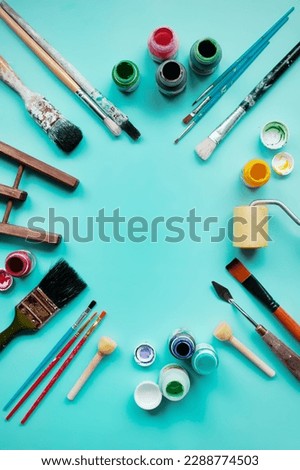 
set of accessories for painting with paints and brushes. fine art tools. creative composition in flatley style on a bright blue or turquoise background. top view. copy space.