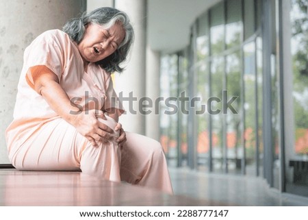 Blurred soft images of an Asian elderly woman has a knee injury, she is a patient of osteoarthritis and osteoporosis, to people health care and osteoarthritis concept. This picture focused on hand