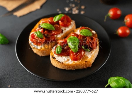 Bruschetta with Ricotto cheese and cherry Tomatoes, basil, garlic on a black background. Food. Food background Royalty-Free Stock Photo #2288779627