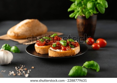 Bruschetta with Ricotto cheese and cherry Tomatoes, basil, garlic on a black background. Food. Food background Royalty-Free Stock Photo #2288779631
