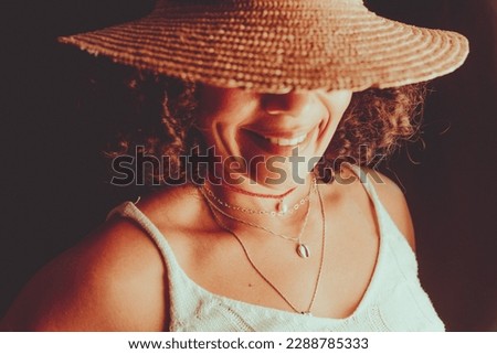 Close-up portrait of a pretty woman wearing a brown hat against a black background.