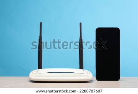 Dual antenna wi-fi router with smartphone on the table, blue background