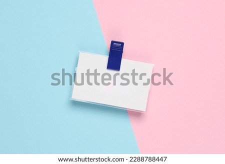 White empty badge on a clip, blue-pink background