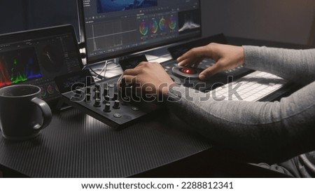 Hands close up of African American video editor working by color grading control panel in studio with modern design. Colorist makes colour correction for movie post production. Professional equipment. Royalty-Free Stock Photo #2288812341