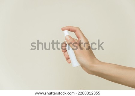 female hand holds a white spray bottle on a gray background. liquid products in spray bottles Royalty-Free Stock Photo #2288812355