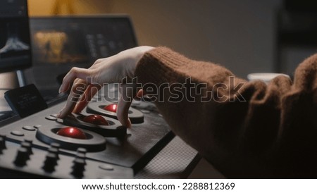 The editor uses digital color grading control panel. Colorist makes video or photo color correction on computer in studio. Tablet with footage and program interface with RGB color wheels at background