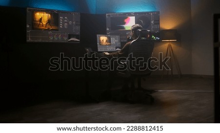 Female editor works in studio on computer using color grading control panel and professional video editing software. Color correction for film post production. Big screens with RGB graphic and levels.