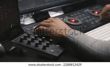 Hands close up of African American video editor working by color grading control panel in studio with modern design. Colorist makes colour correction for movie post production. Professional equipment.