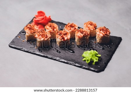 Maki Sushi Rolls with salmon on black stone on dark background. With ginger and wasabi. Sushi menu. Japanese food. Closeup of delicious japanese food with sushi roll. Horizontal photo