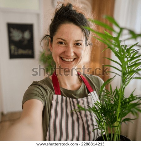 One Young woman caucasian female gardener or florist portrait take care and cultivate domestic flowers plants at home gardening concept UGC user generated concept self portrait Royalty-Free Stock Photo #2288814215