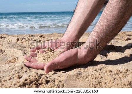 Touching the beach. Shot of a man with a handful of sand falling through his fingers.