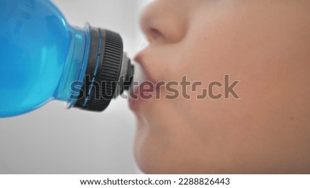 Taking a break. Side view of sporty teenager drinking blue energy drink. Youth and sports Royalty-Free Stock Photo #2288826443