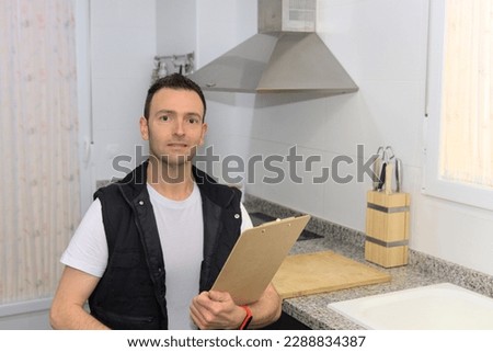 Electro mechanic repairman looking at camera by counter in kitchen smiling confident Royalty-Free Stock Photo #2288834387