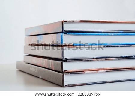photobooks stacked on top of each other on a white table. the concept of making books and albums from photos. services of a professional photographer and printing house.