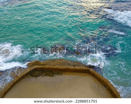 Overhead aerial shot of the vast green ocean water with waves crashing into the rocks at Victoria Beach in Laguna Beach California USA