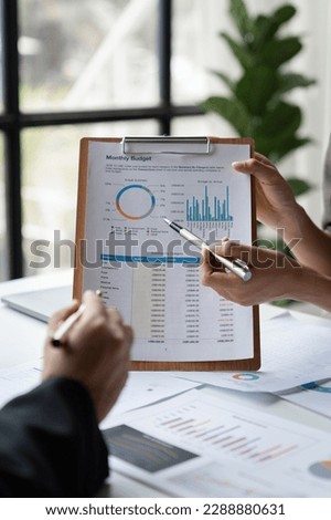 Team of business people is calculating with a calculator and discussing to record company financial growth statistics using graphs. The chart is a reference for auditing and analyzing the summary.