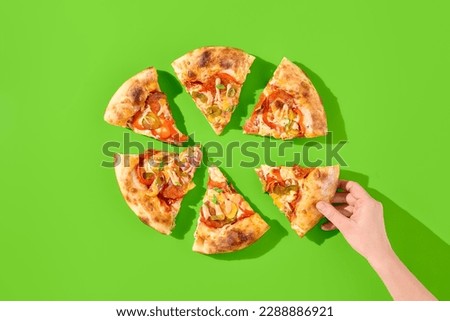 American pizza with salami, pepperoni, and jalapeno on a bright green background, featuring hard shadows and minimalist style. A female hand grabbing a slice. Perfect for a casual meal or to-go. Royalty-Free Stock Photo #2288886921