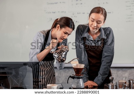 Young adult baristas follow recipes to create artisan and specialty beverages. Making drip coffee with a unique way. Small business owners practice the sense of taste and scent at slow bar coffee. Royalty-Free Stock Photo #2288890001