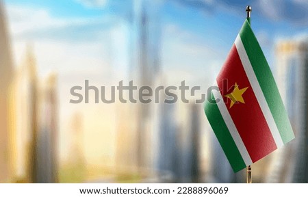 Small flags of the Suriname on an abstract blurry background.