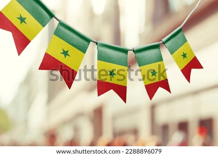 A garland of Senegal national flags on an abstract blurred background.