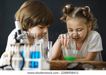 Children scientists. Schoolchildren in laboratory conduct experiments. Boy and girl experiments with a microscope.