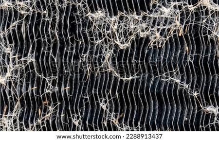 Macro of seed pods and dust collecting on the heat exchanger coils of an air conditioner outside.  Royalty-Free Stock Photo #2288913437