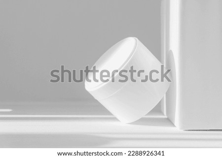 Mockup of white jar for packaging cosmetics on isolated background. Container with moisturizer without marking close-up against white wall, in rays of sunlight. Concept of skin care, rejuvenation Royalty-Free Stock Photo #2288926341