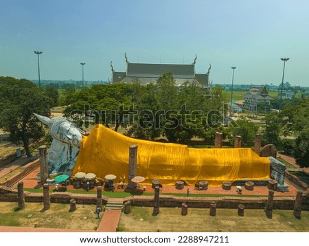 aerial view above the big beautiful reclining Buddha at Wat Khun Inthapramun Ang thong Thailand.
The golden yellow robe covers the white reclining Buddha image.
 blue sky background.
