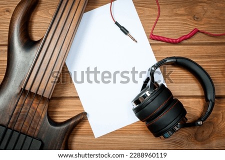 Mockup with a white sheet of paper with a guitar and headphones for music themes and drawings.